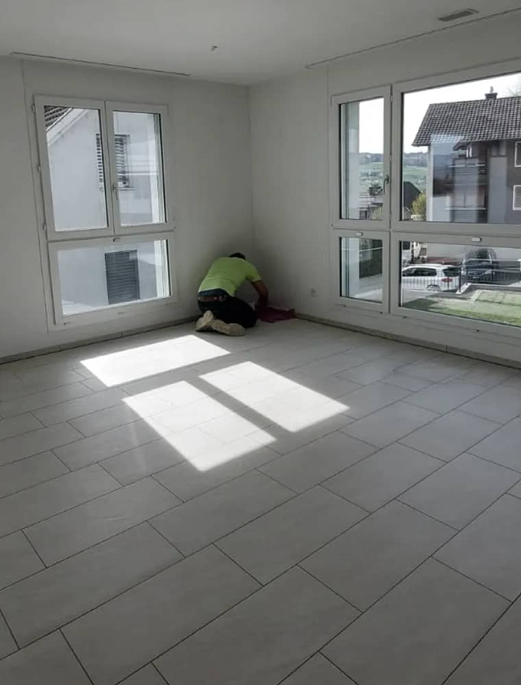Collaboratrice de Reinigungsfee lors du nettoyage final d’un appartement, soleil sur le carrelage.